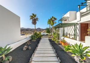 a walkway in front of a house with palm trees at B13-Dúplex luminoso+ piscina a 150 m del mar in Charco del Palo