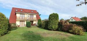 ein Haus mit einem roten Dach und einem Hof in der Unterkunft Ferienwohnung Gartentraum mit tollem Rasengarten in Ostseebad Karlshagen