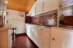 cocina con armarios blancos y suelo de baldosa roja en Clair Abri 104, en Verbier
