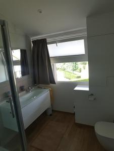 a bathroom with a tub and a sink and a window at Huisje aan zee in Middelkerke