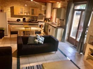 a living room with a couch and a kitchen at Les Vieilles Ombres in Bagnizeau