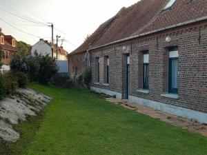 een lege tuin naast een bakstenen gebouw bij La ferme des 2 chartreuses in Gosnay