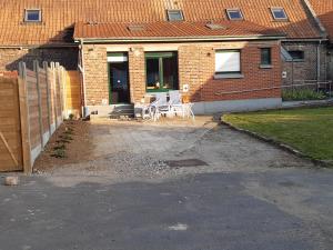 een huis met een patio met een tafel en stoelen bij La ferme des 2 chartreuses in Gosnay