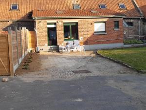 a house with a patio with a table and chairs at La ferme des 2 chartreuses in Gosnay