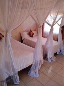 IsioloBomen Hotel的卧室内的两张床,带白色窗帘