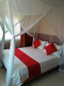 a bed with red and white pillows in a room at Bomen Hotel in Isiolo