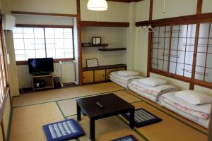 那智勝浦町にあるお宿 はなのベッド3台、テーブル、テレビが備わる客室です。