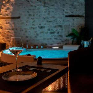 a glass of wine sitting on a table next to a swimming pool at LOVE Suites & SPA "Le Chai" avec lit rond in Médis