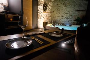 a table with two wine glasses and a bath tub at LOVE Suites & SPA "Le Chai" avec lit rond in Médis