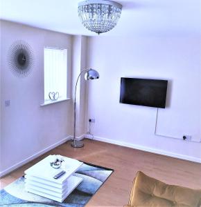 a living room with a table and a flat screen tv at Salford Holiday Apartment Manchester in Manchester