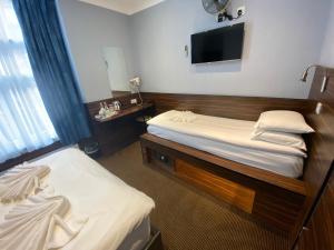 a hotel room with two beds and a flat screen tv at Crestfield Hotel in London +69 photos