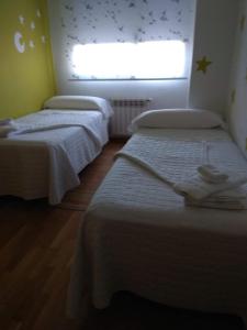 2 Betten in einem kleinen Zimmer mit Fenster in der Unterkunft Lujo en el Centro in Castellón de la Plana