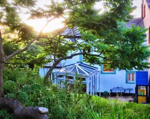 una casa azul con un árbol delante en The Tree House Cumbria en Beckermet