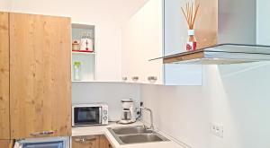 eine Küche mit einer Spüle und einer Mikrowelle in der Unterkunft Casa Gina Garden and view by Gardadomusmea in Tremosine sul Garda