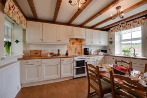 a kitchen with white cabinets and a table and chairs at Middlehead Cottages in Pickering