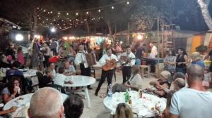 een groep mensen die een band zien spelen op een evenement bij Happy Camp Mobile Homes in El-Bahira Camping Village in San Vito lo Capo