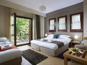 a hotel room with two beds and a balcony at Pilion Terra Hotel in Portariá