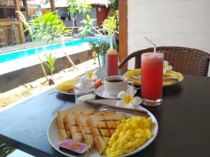 a table with a breakfast of eggs and waffles and juice at Villa PhyPhy in Gili Trawangan
