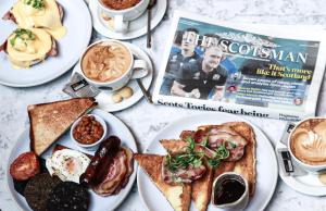 a table topped with plates of food and a magazine at Le Monde Hotel in Edinburgh