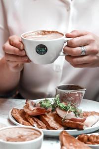 a person holding a cup of coffee over a plate of food at Le Monde Hotel in Edinburgh