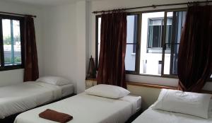 three beds in a room with two windows at Aunt & Uncle's House in Chiang Mai