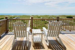two white chairs sitting on a deck looking at the ocean at Dune Deck North - Duplex in Holden Beach