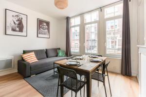 een woonkamer met een tafel en een bank bij Cosy appartement proche gares #2 in Lille