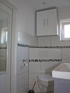 een witte badkamer met een toilet en een wastafel bij Ferienhaus Domizil Wattenmeer in Friedrichskoog