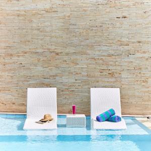 two white chairs sitting next to a swimming pool at Echo Bali Beach Villas by The Kunci in Canggu