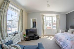 um quarto com uma cama, um sofá e uma televisão em Olivers Guest House em Weymouth