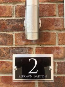 a sign on the side of a brick wall at 2 Crown Barton in Glastonbury