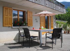 a table with chairs and an umbrella in front of a house at Le Berceau Savoyard - Annecy in Nâves-Parmelan
