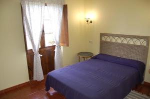 1 dormitorio con cama morada y ventana en Apartamentos Rurales La Regatina, en Lamuño