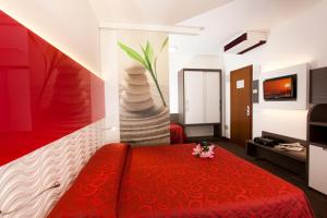 una camera d'albergo con letto rosso e TV di Hotel Lilia a Lido di Jesolo