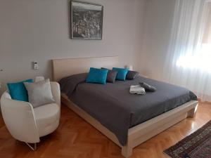 un letto con cuscini blu e una sedia in una stanza di FUSNAR a Aquilinia