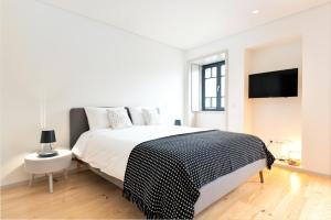 a white bedroom with a bed and a flat screen tv at Bom Jardim Apartments in Porto