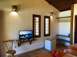 a living room with a flat screen tv on the wall at Hotel Pousada Beleza das Ondas in Cumbuco