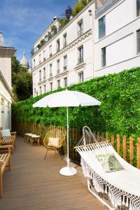 a patio with a white umbrella and chairs and a building at Le Village Montmartre by Hiphophostels in Paris