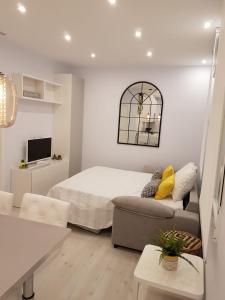 a white bedroom with a bed and a couch at Apartamento con encanto in Madrid