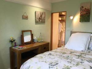 1 dormitorio con cama y escritorio con espejo en East Hillerton House, en Crediton