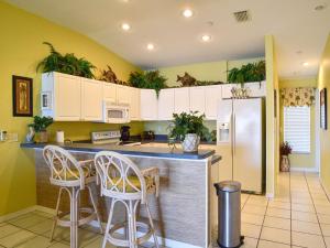 a kitchen with white cabinets and a counter with stools at Gulf Retreat 2: Magnificent Water Views, Steps to Beach, None Cleaner, None Nicer! in Clearwater Beach
