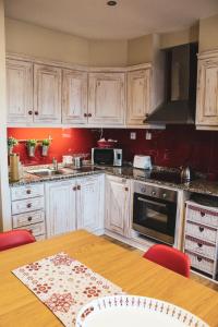 a kitchen with white cabinets and a wooden table at Casinha dos Relógios in Penhas da Saúde
