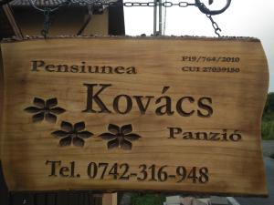 ein hölzernes Schild, das an einer Kette hängt in der Unterkunft Kovács Guesthouse in Praid