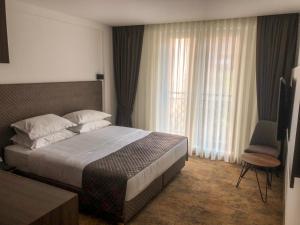 a hotel room with a bed and a chair at Qama Hotel in Pristina