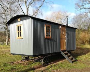 多切斯特Gaggle of Geese Pub - Shepherd Huts & Bell Tents的田野上的一个车上的小房子