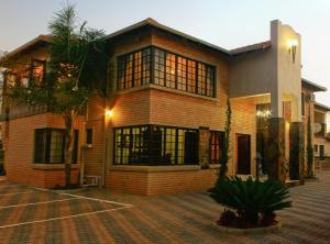 a brick house with a palm tree in front of it at Eco Park Lodge in Centurion