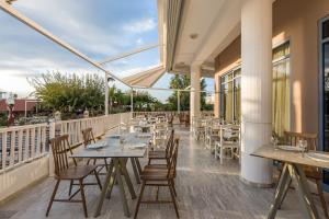 a restaurant with tables and chairs on a balcony at Ariadne Hotel in Platanes