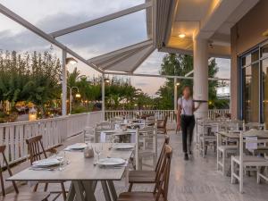a woman walking through a restaurant with tables and chairs at Ariadne Hotel in Platanes