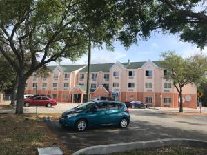 a small car parked in a parking lot in front of a building at Days Inn & Suites by Wyndham Tampa/Raymond James Stadium in Tampa