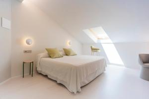 a white bedroom with a bed and a skylight at Fonda Llabres Boutique in Alcudia